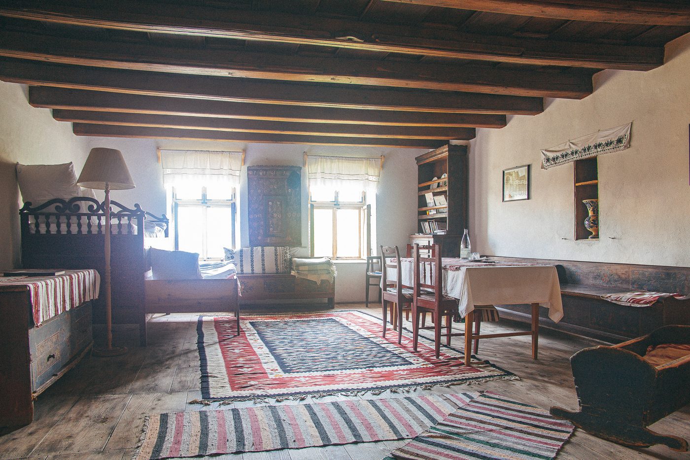 Interior tradițional săsesc din Viscri — grinzi de lemn, covoare țesute și mobilier pictat