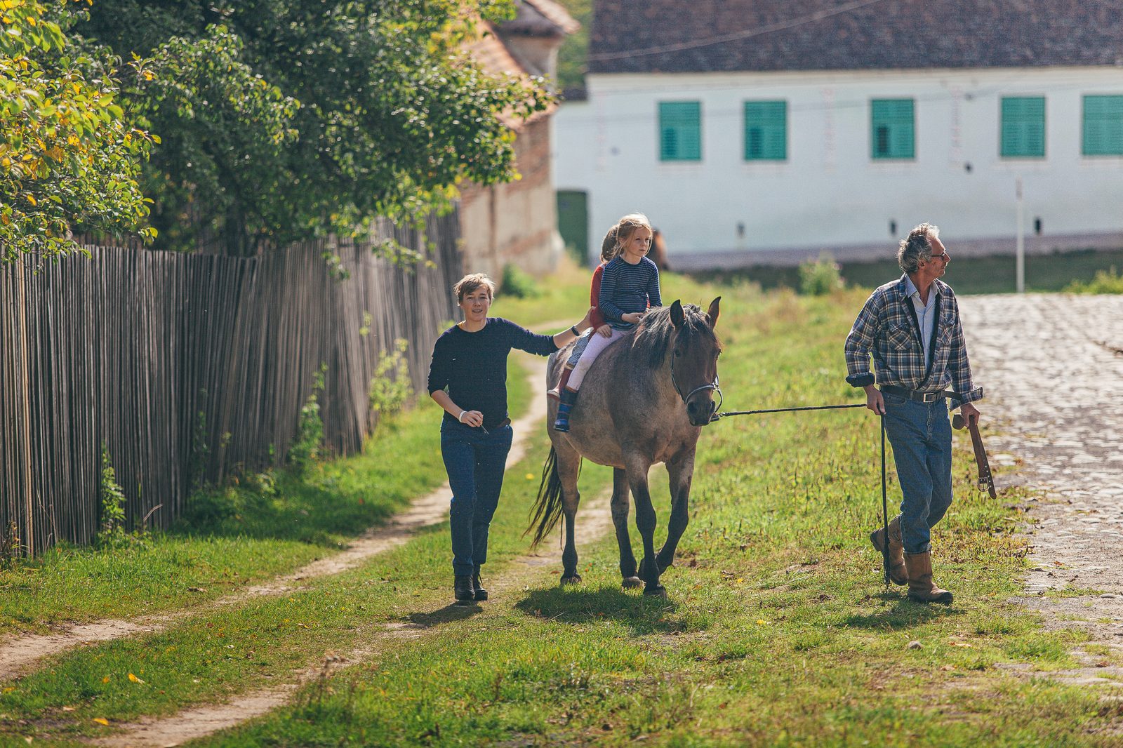 Familie plimbând un cal pe ulița satului, într-o zi de toamnă în comuna Bunești
